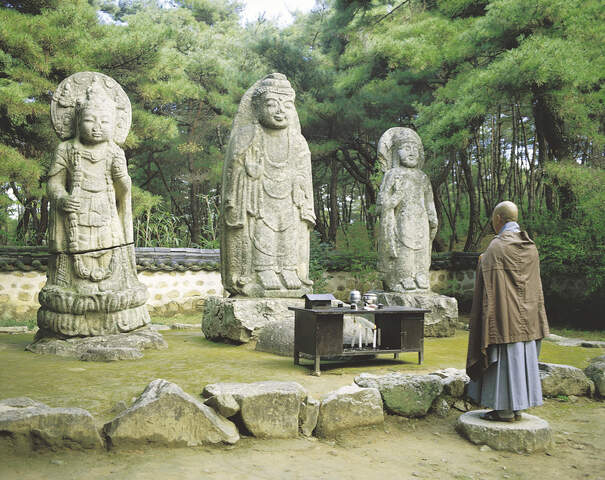 Mönch vor Buddha-Statuen